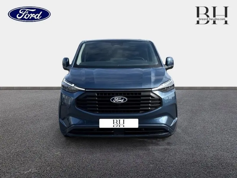 Vue frontale du Ford Transit Custom Fourgon 2025 en bleu azur métallisé avec calandre noire et phares LED fins.