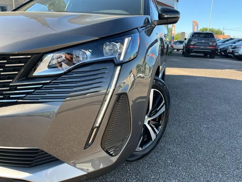 Gros plan sur l'avant droit gris Artense du Peugeot 5008 2024, mettant en valeur le phare LED et la jante alliage.