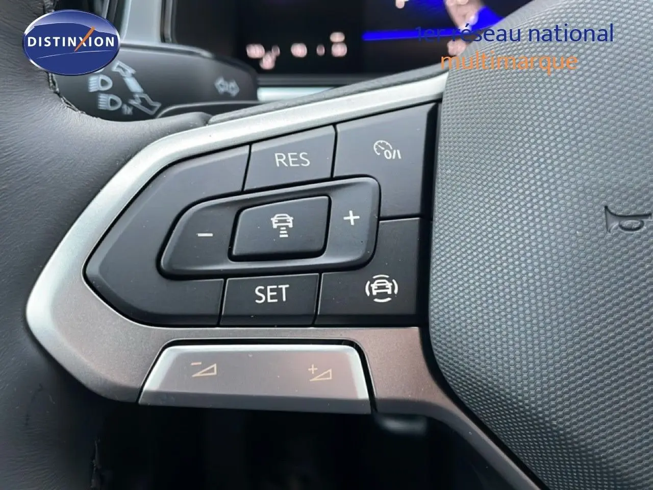 Gros plan sur les commandes au volant du Volkswagen T-Roc noir Grenadilla, mettant en valeur les boutons de régulateur de vitesse.