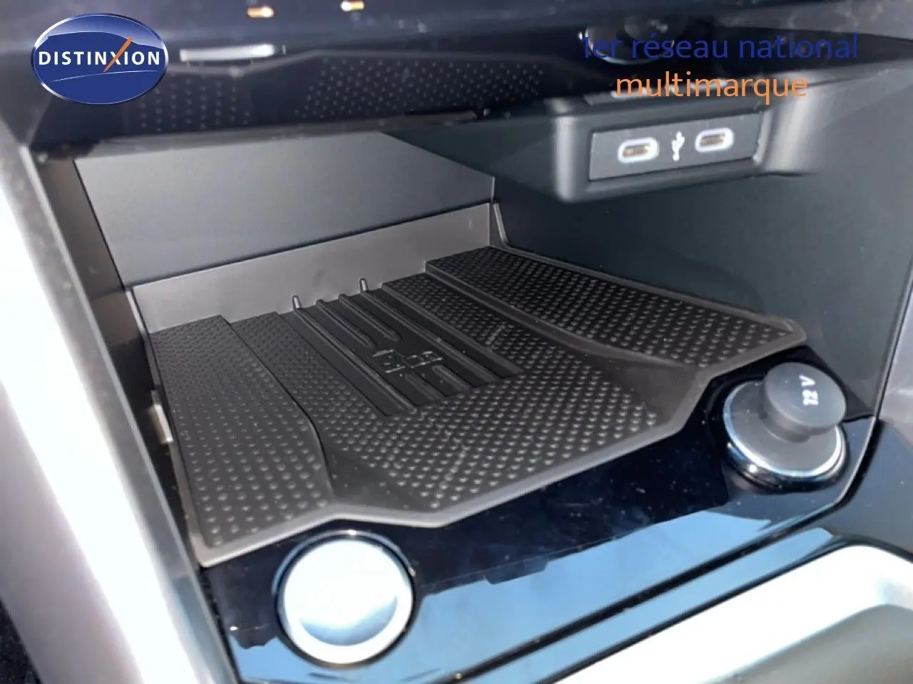 Vue rapprochée de la console centrale du Volkswagen T-Roc noir, mettant en valeur le chargeur sans fil et les ports USB.