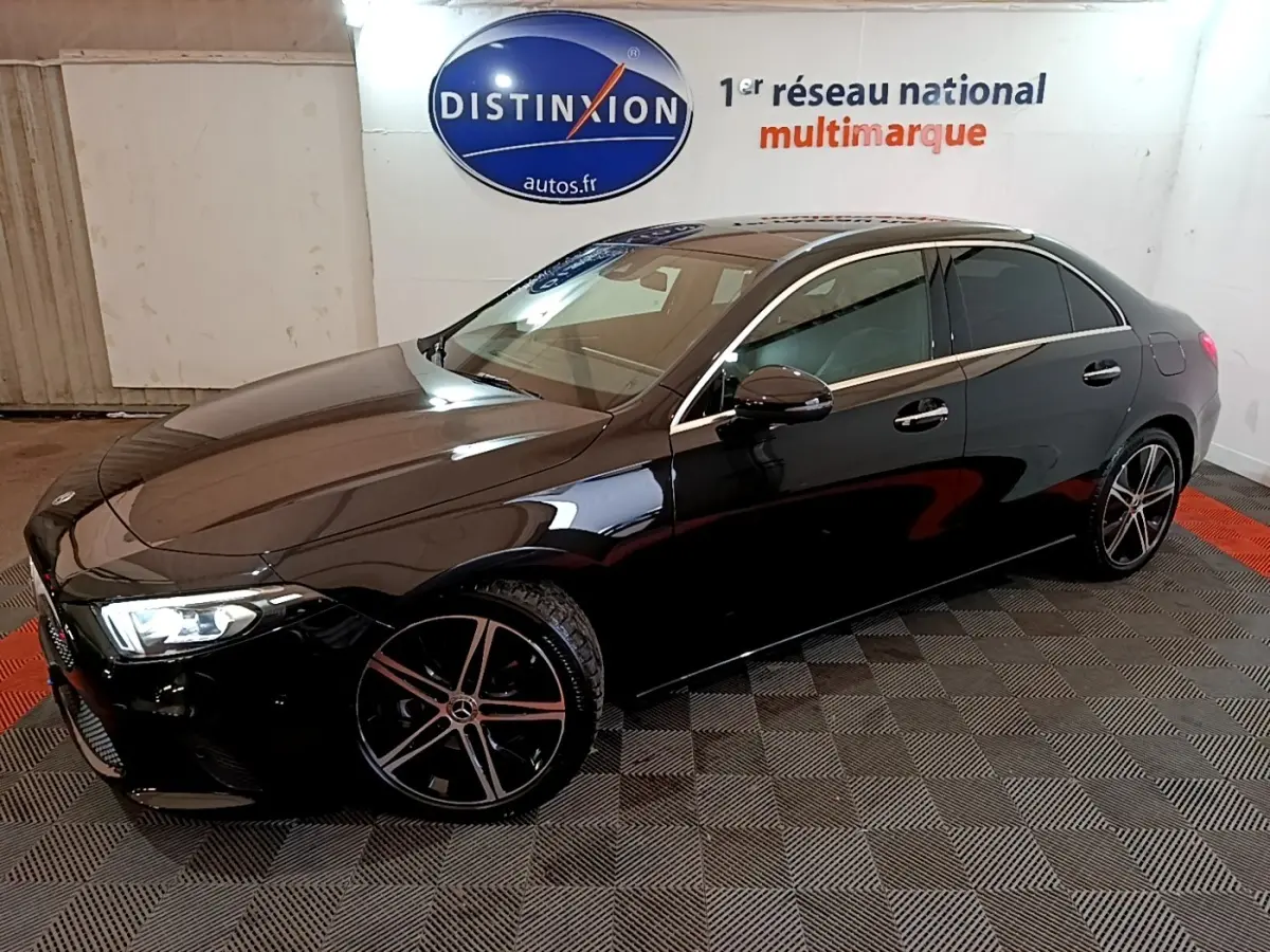 Mercedes Classe A Berline noire vue en 3/4 avant droit, avec jantes alliage et feux LED allumés dans un showroom.