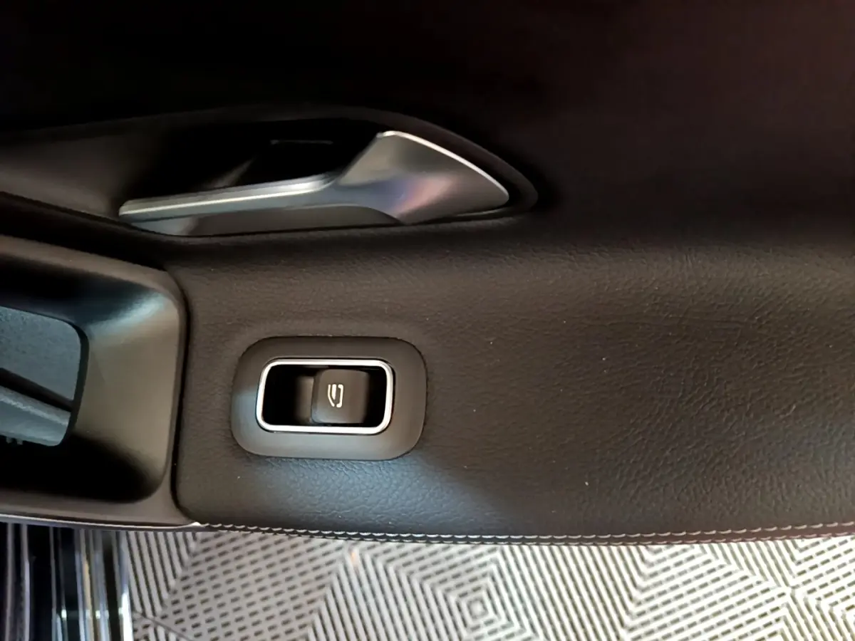 Détail de la commande électrique de la lunette arrière sur la porte intérieure côté gauche d’une Mercedes Classe A noire.