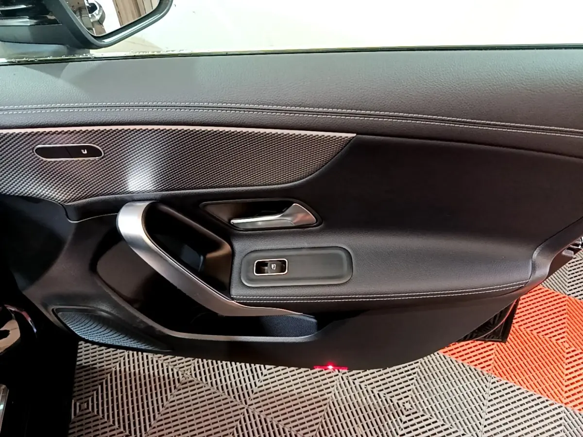 Vue intérieure côté gauche de la porte avant d’une Mercedes Classe A noire, avec garniture cuir et inserts argentés.