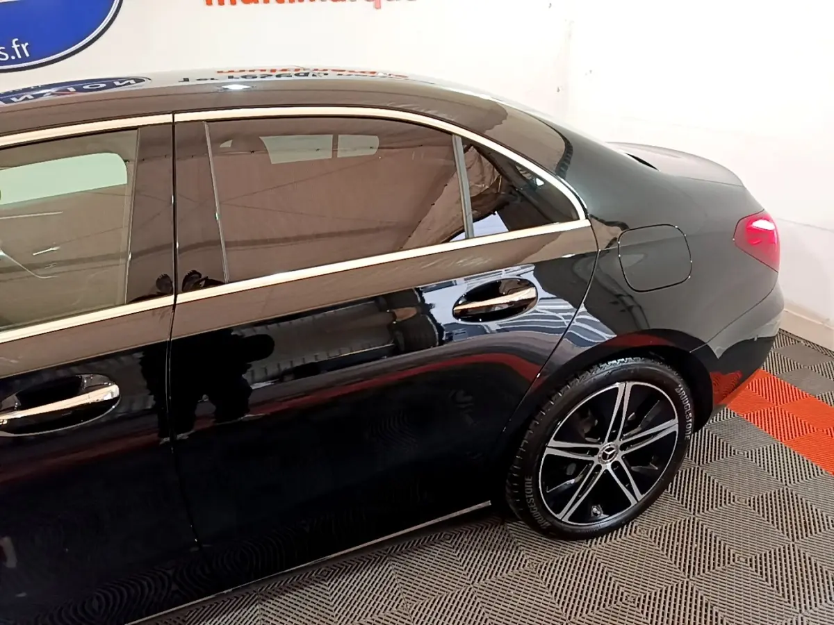 Vue latérale droite d'une Mercedes Classe A Berline noire, mettant en valeur les jantes alliage et les poignées chromées.