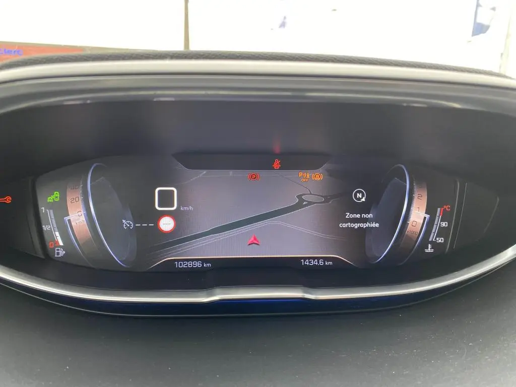 Tableau de bord numérique du Peugeot 3008 blanc, affichant la navigation et les indicateurs de vitesse et température.