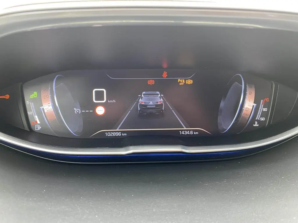 Affichage numérique du tableau de bord du Peugeot 3008 blanc, montrant la vitesse à 0 km/h et l'alerte de distance de sécurité.