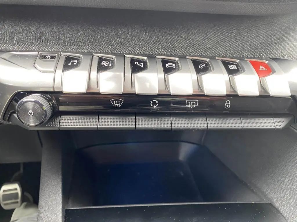 Gros plan sur la rangée de commandes chromées et boutons noirs du tableau de bord du Peugeot 3008 blanc 2018.