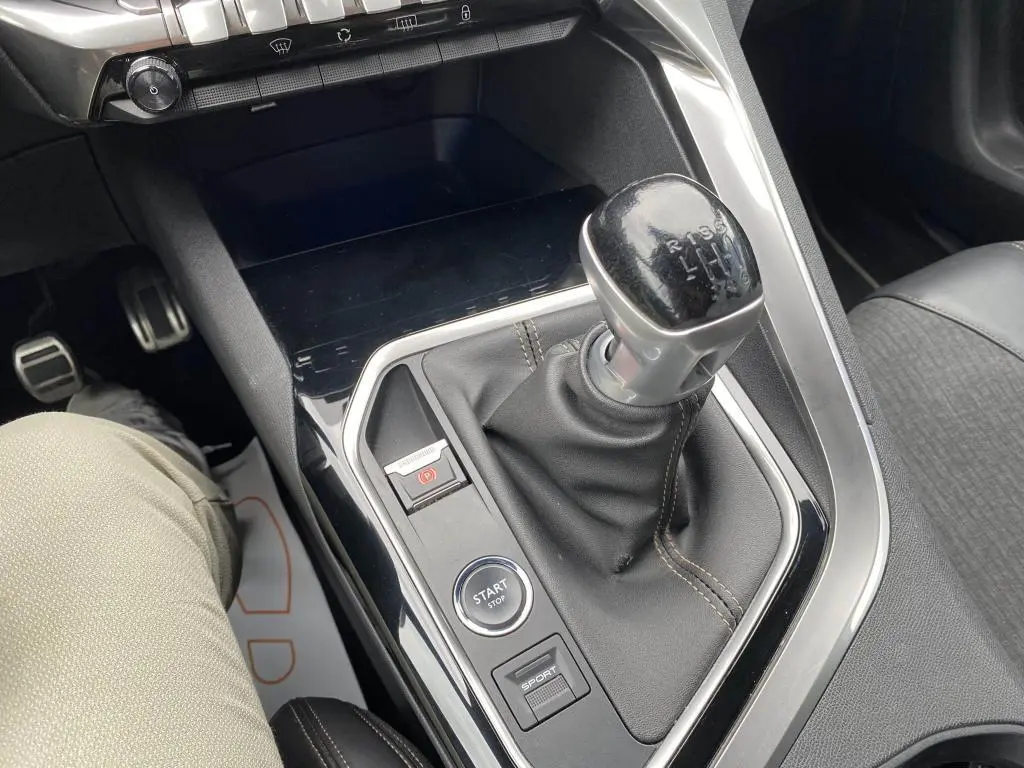 Gros plan sur la console centrale du Peugeot 3008 blanc 2018, mettant en valeur la boîte manuelle et le bouton Start/Stop.