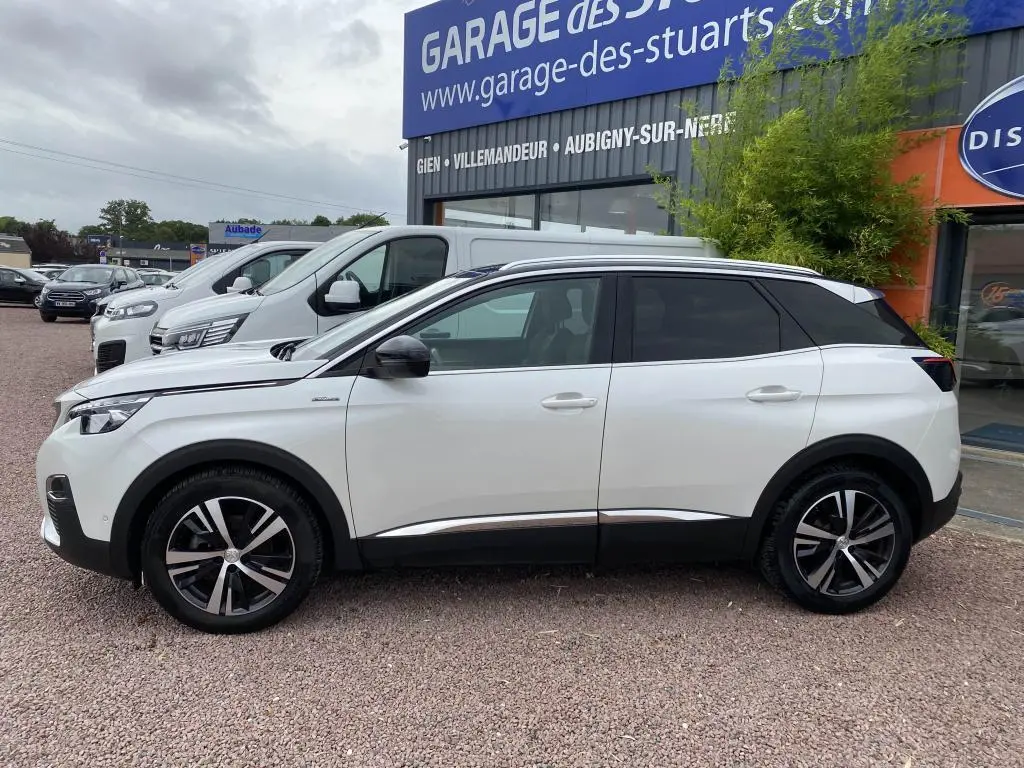 Profil droit d'un Peugeot 3008 blanc nacré GT Line avec barres de toit aluminium et jantes alliage bicolores.