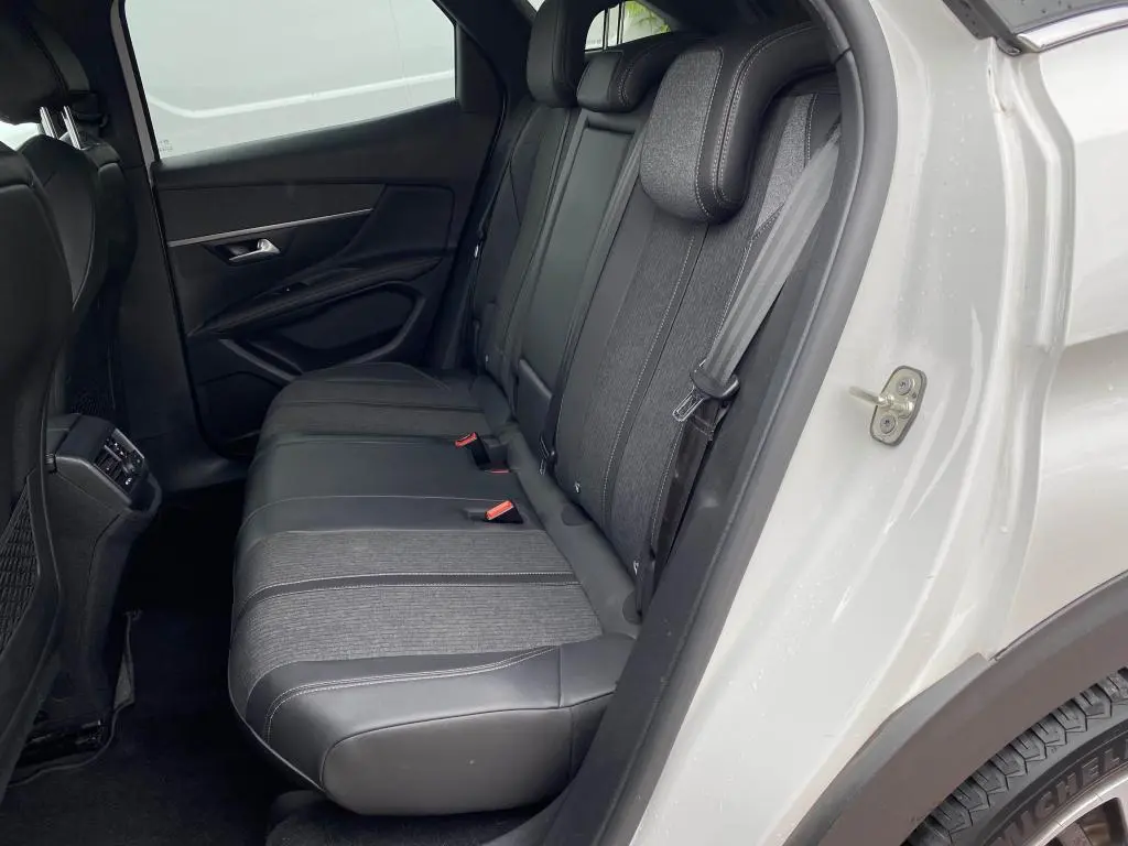 Vue côté gauche des sièges arrière en tissu et cuir noir du Peugeot 3008 blanc nacré 2018 avec porte ouverte.