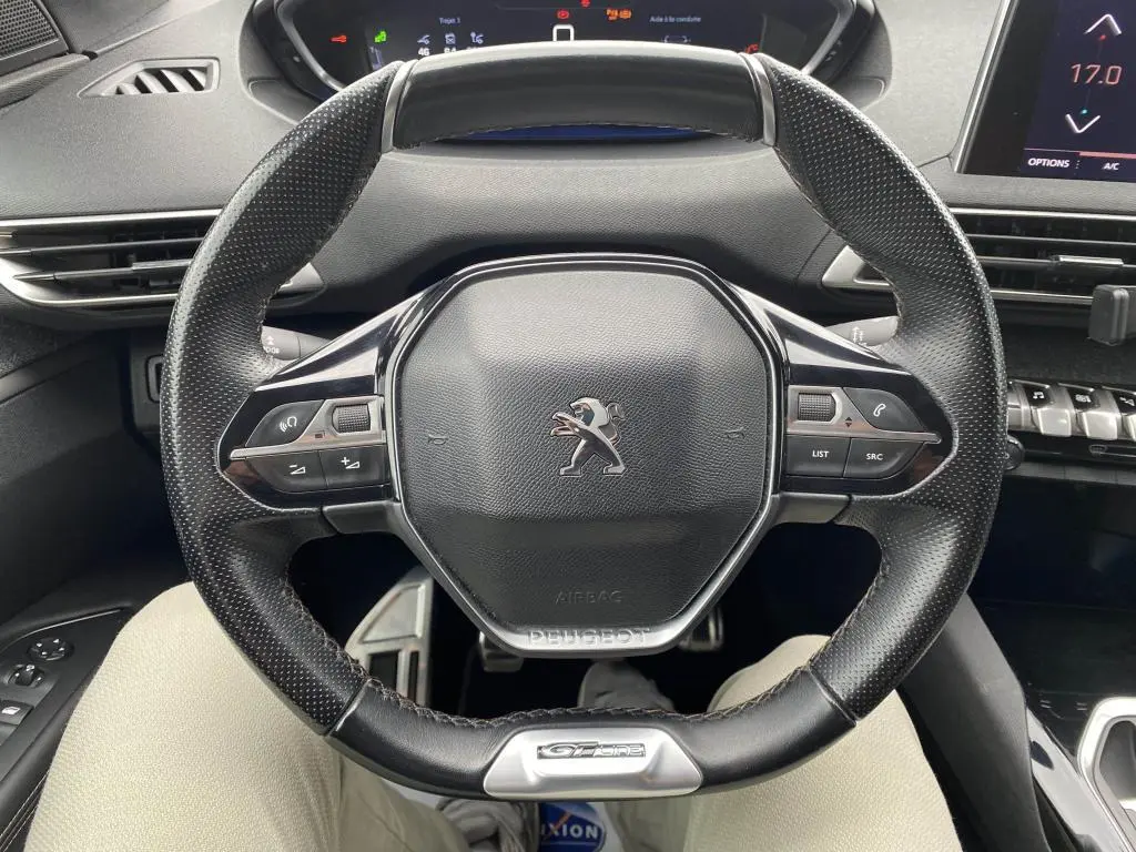 Vue rapprochée du volant compact en cuir perforé avec logo Peugeot et badge GT Line du 3008 blanc de 2018.
