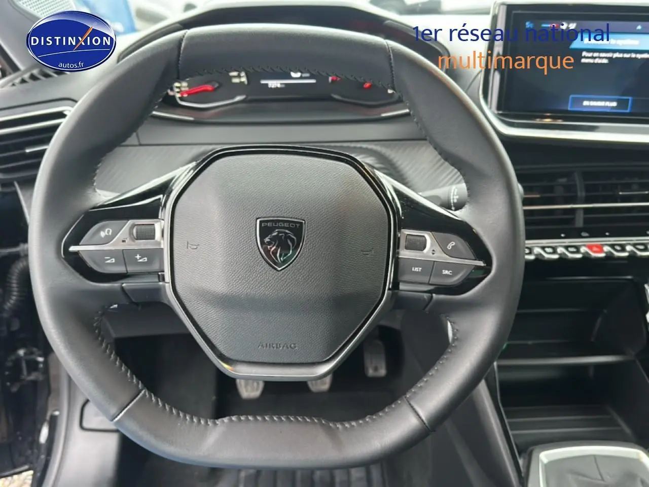 Vue rapprochée du volant cuir noir de la Peugeot 208 1.2 100 style avec commandes intégrées et tableau de bord numérique.