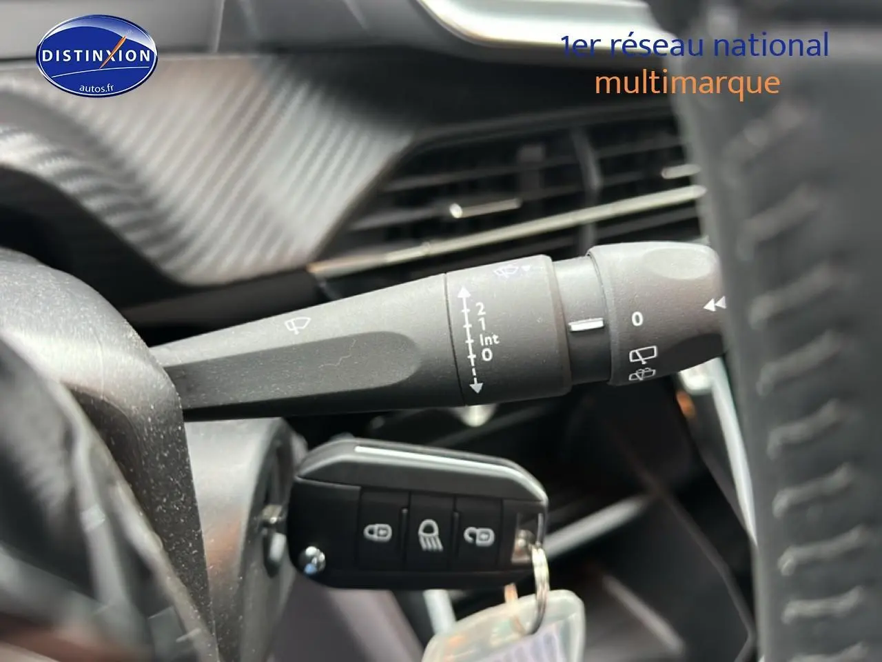 Gros plan sur la manette d’essuie-glace et la clé de contact dans l’habitacle d’une Peugeot 208 noire 2025.