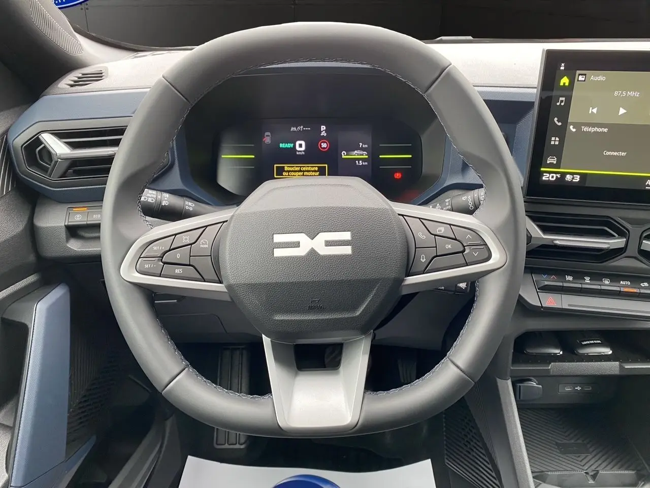 Vue centrée sur le volant et le tableau de bord du Dacia Duster Full Hybrid 140 gris schiste, avec écran tactile et commandes intégrées.