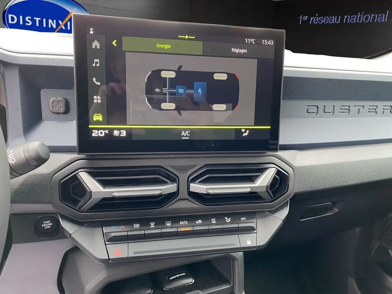 Vue intérieure du tableau de bord du Dacia Duster 2025 gris schiste, avec écran tactile et aérateurs hexagonaux.