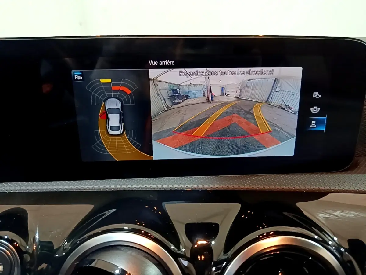 Écran tactile intérieur de la Mercedes CLA 200 d blanc, affichant la caméra de recul avec aides au stationnement.