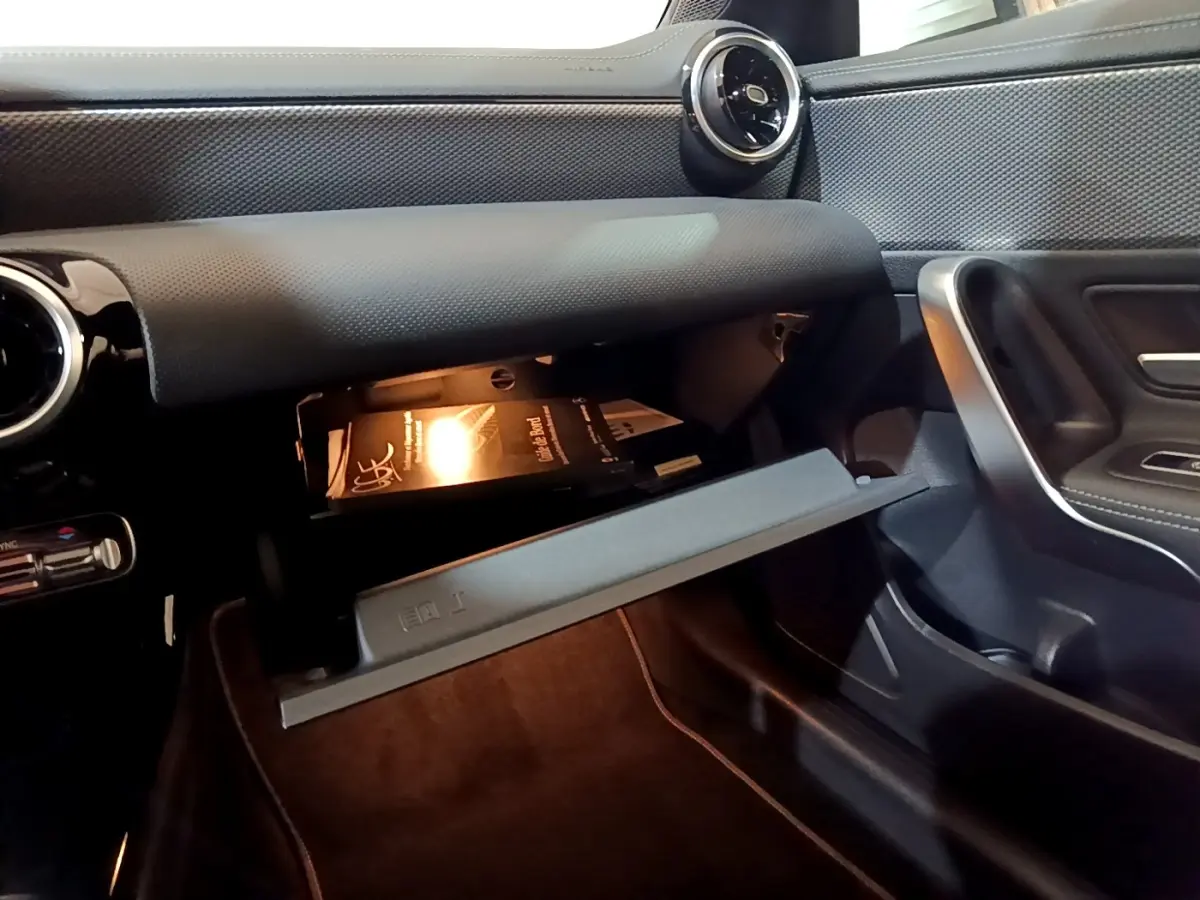 Intérieur de la Mercedes CLA 200 d Business Line 2021, vue côté passager sur boîte à gants ouverte avec manuel visible.