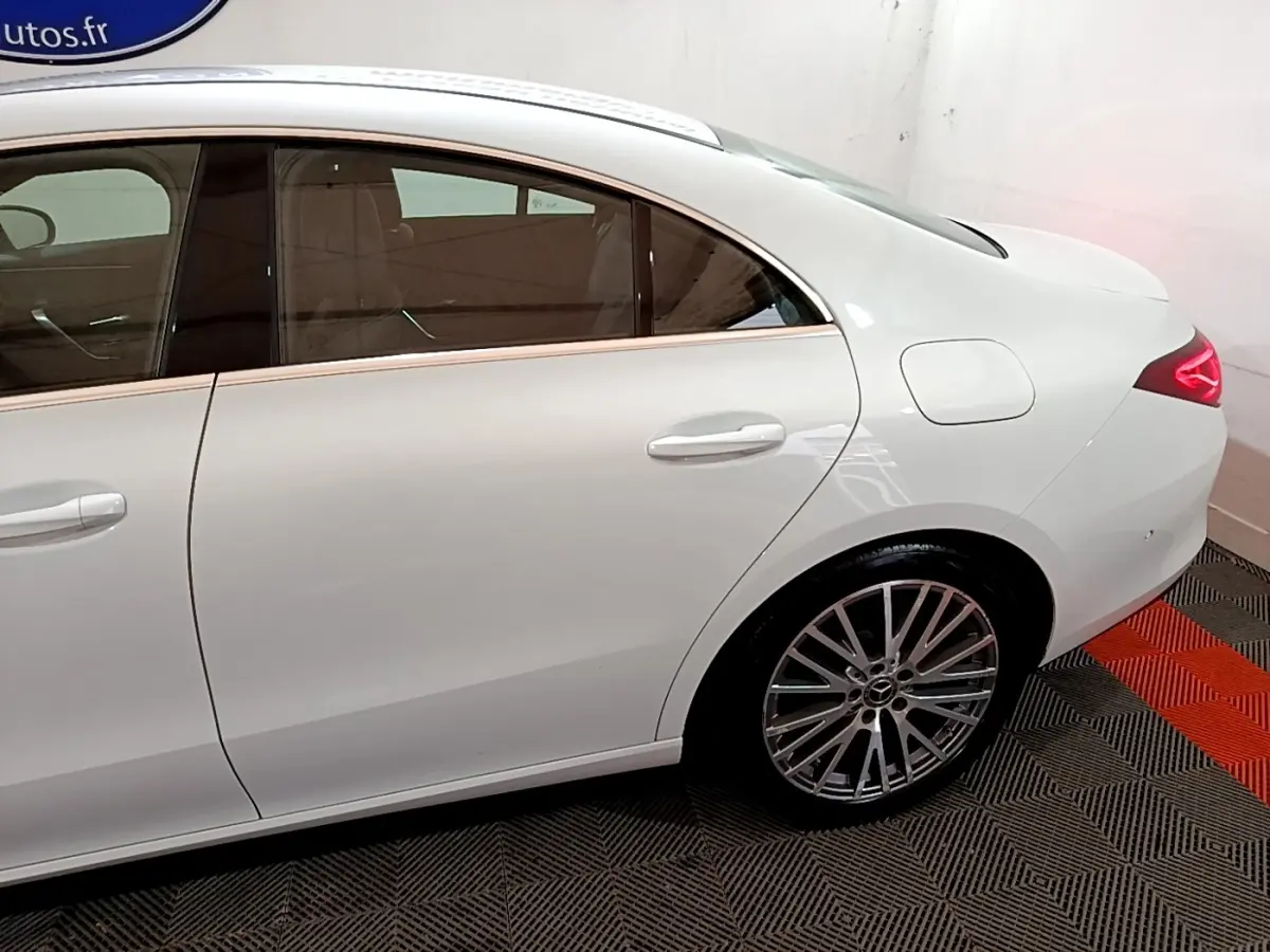 Vue côté droit arrière d'une Mercedes CLA 200 d Business Line blanche avec jante alliage et feux LED allumés.