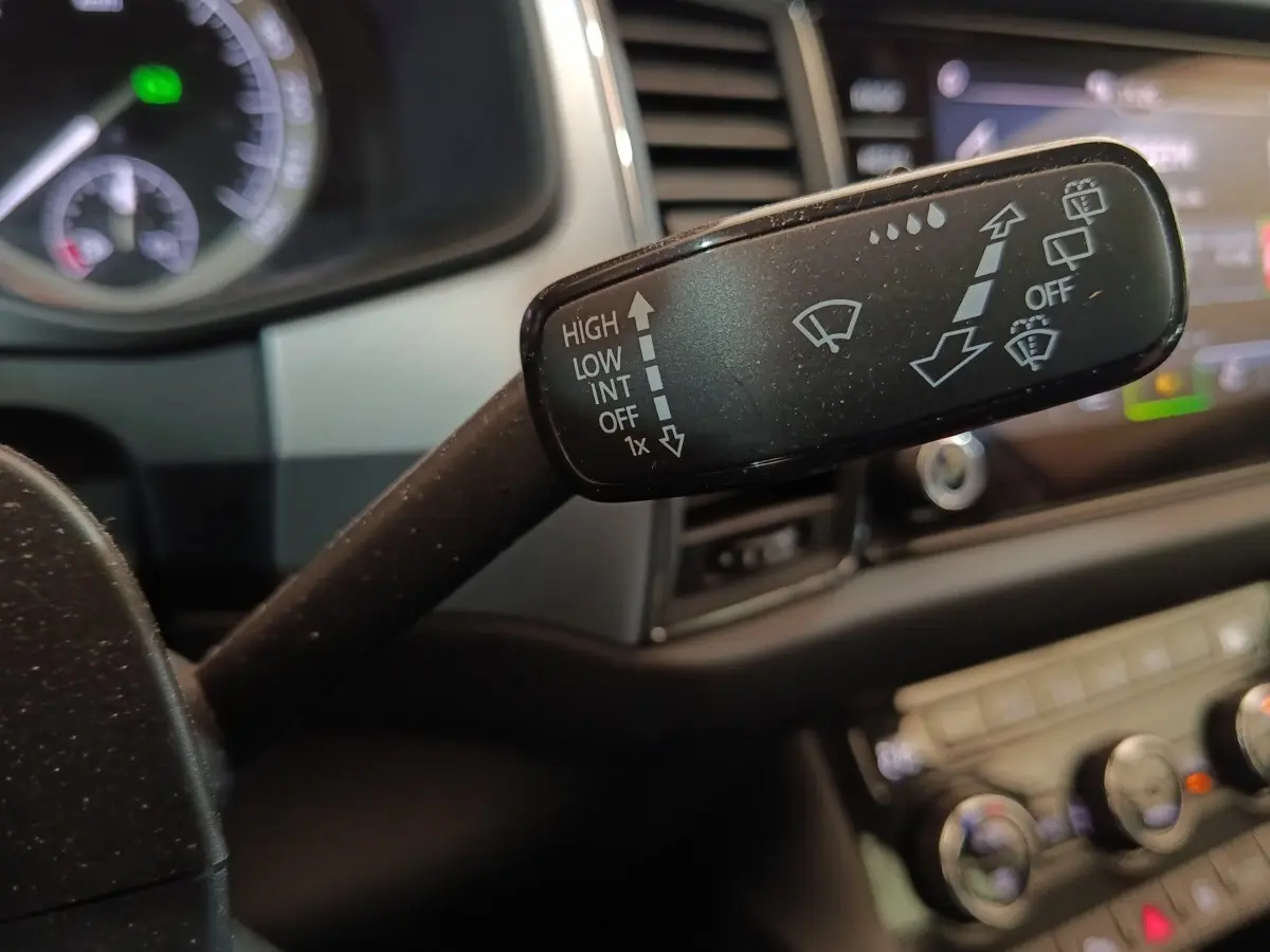 Gros plan sur la commande des essuie-glaces dans l’habitacle du Skoda Kodiaq blanc, tableau de bord en arrière-plan flou.