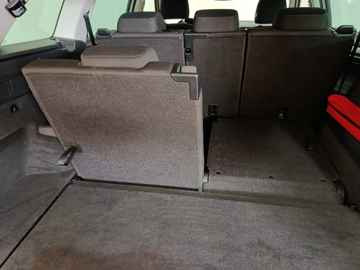 Vue arrière du coffre du Skoda Kodiaq blanc 2022, montrant la troisième rangée de sièges partiellement rabattue en tissu gris.