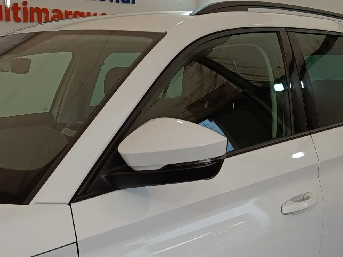 Vue côté gauche avant d'un Skoda Kodiaq blanc, mettant en valeur le rétroviseur et la poignée de porte.