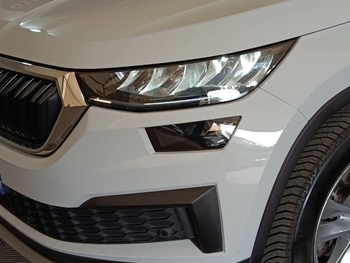 Gros plan sur l’avant droit blanc du Skoda Kodiaq 2022, mettant en valeur le phare LED et la calandre noire.