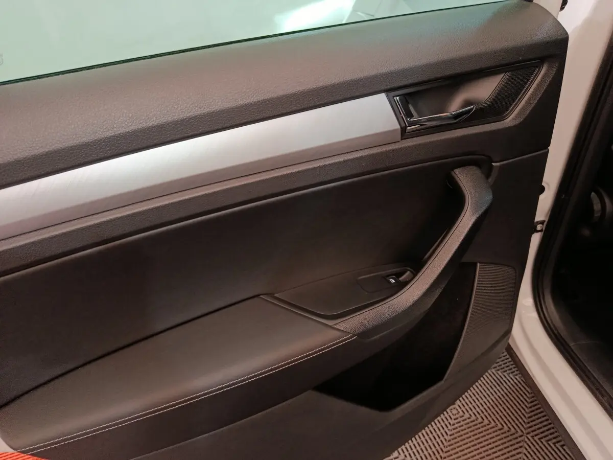 Gros plan sur la porte intérieure côté conducteur du Skoda Kodiaq blanc, avec garniture noire et insert aluminium brossé.