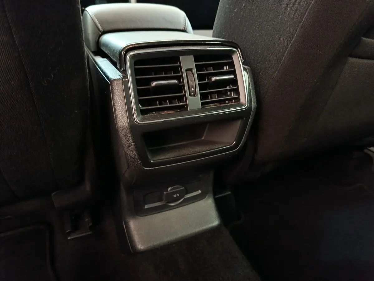 Vue rapprochée des aérateurs arrière noirs et prise 12V au dos des sièges avant dans un Skoda Kodiaq blanc.