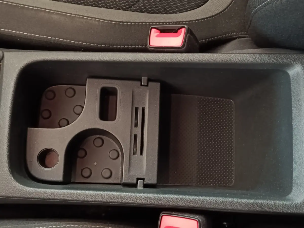 Gros plan sur le rangement central noir avec porte-cartes et ceintures de sécurité rouges dans un Skoda Kodiaq blanc.