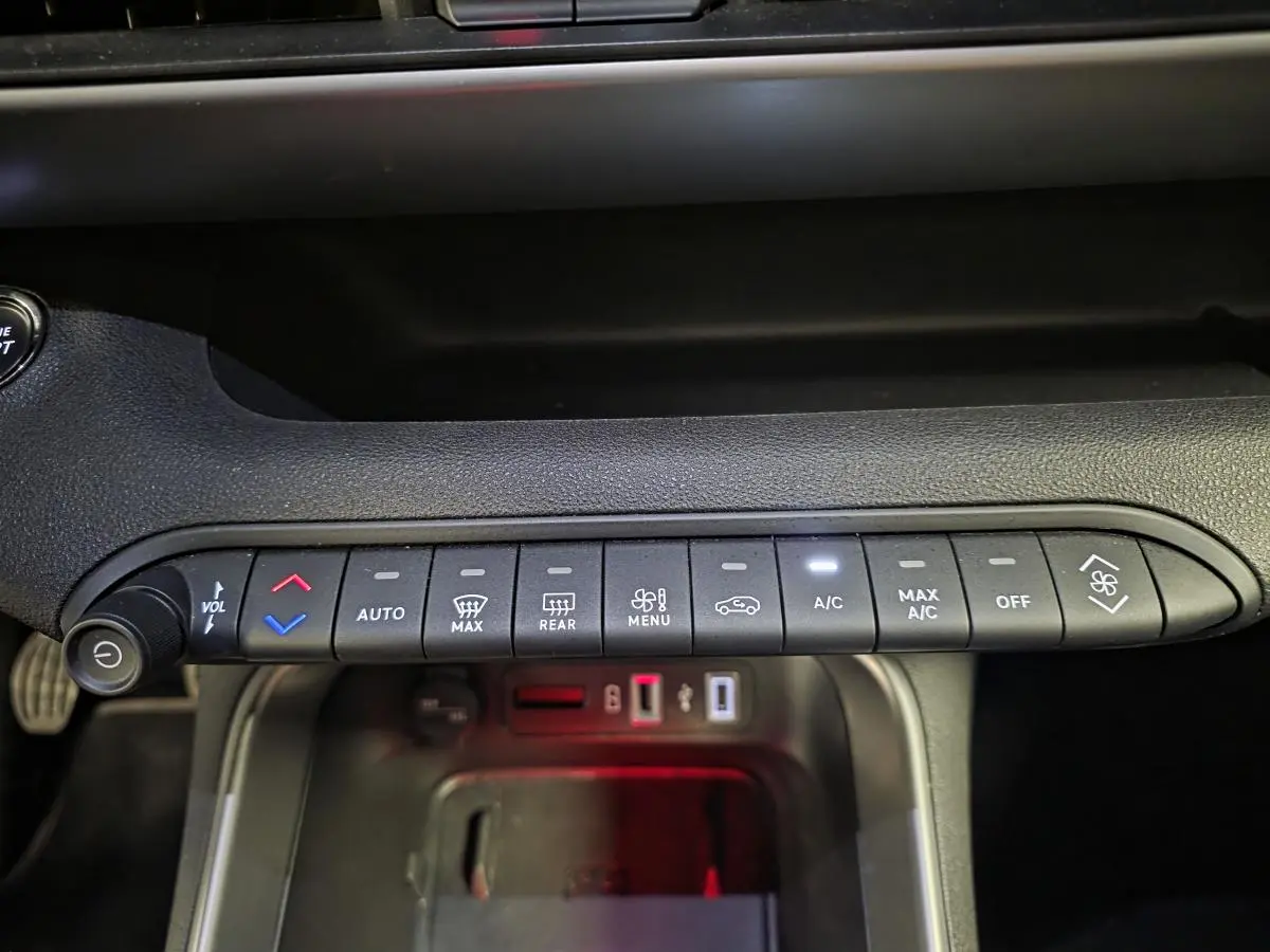 Vue rapprochée de la console centrale du Jeep Avenger noir 2025, montrant les commandes de climatisation et volume.