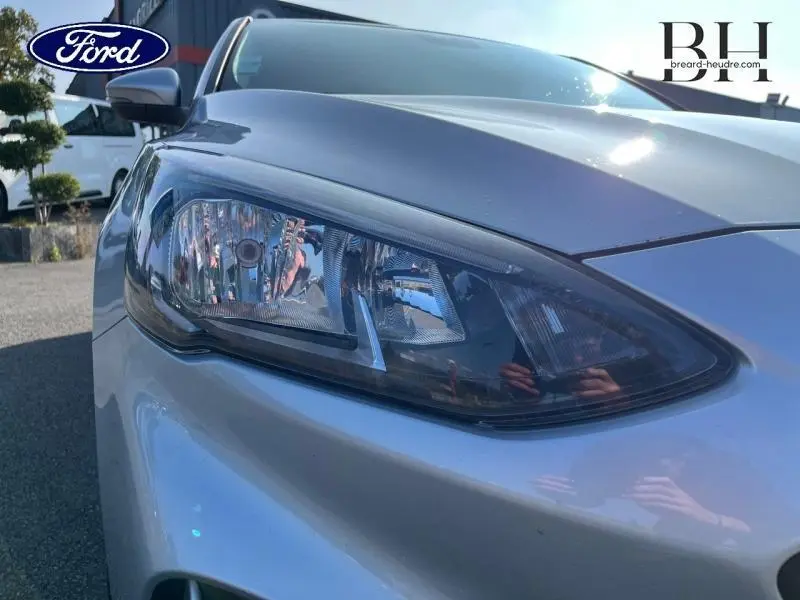 Gros plan sur le phare avant gauche d'une Ford Focus gris lunaire 2019, mettant en valeur son design moderne.