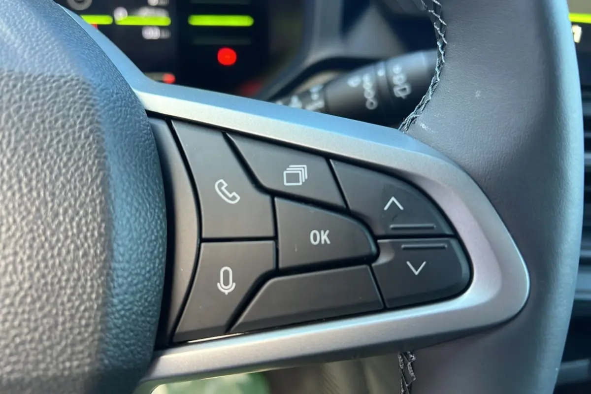 Gros plan sur les commandes multifonctions à droite du volant du Dacia Duster blanc glacier 2025, version Journey Plus.