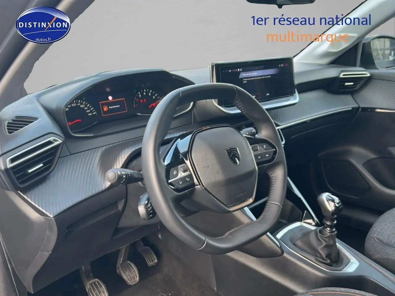 Vue intérieure côté conducteur du tableau de bord et volant de la Peugeot 208 gris Artense avec boîte manuelle.