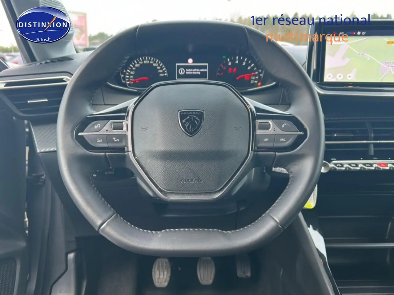 Vue centrée sur le volant noir de la Peugeot 208 1.2 100 Style 2025 avec tableau de bord et écran tactile visible.