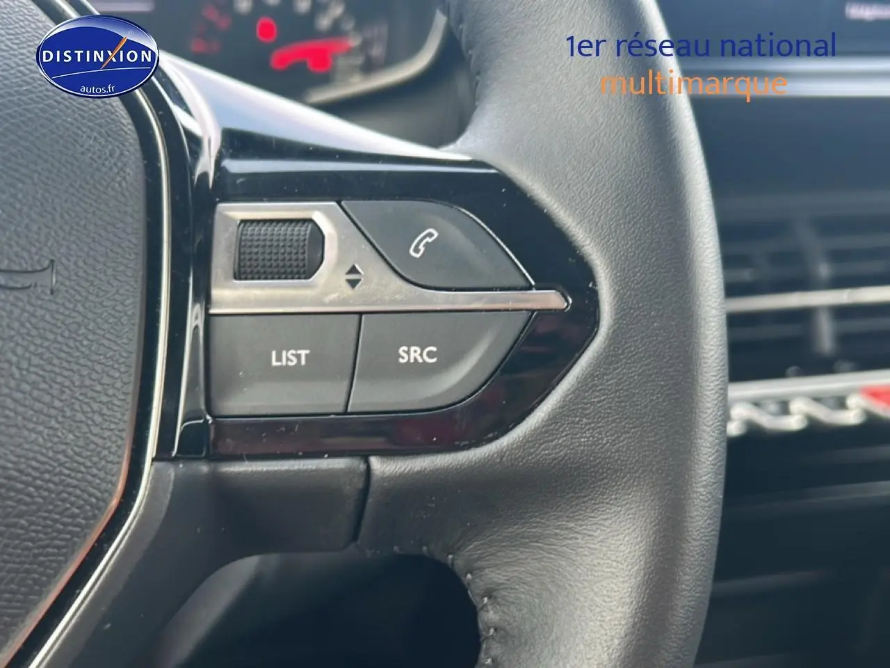 Gros plan sur les commandes audio au volant noir du Peugeot 208 1.2 100 style gris artense, intérieur moderne.
