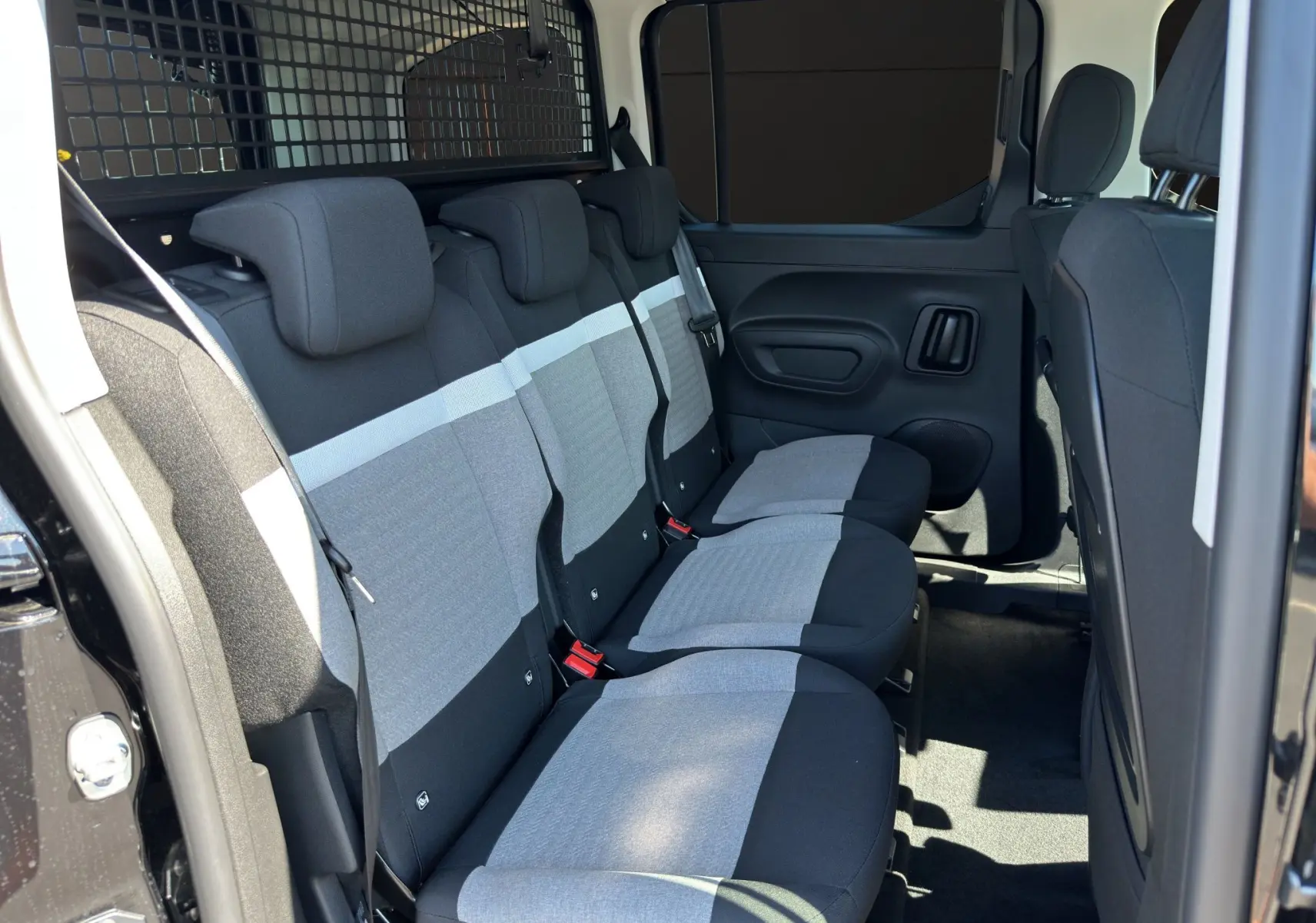 Vue intérieure côté droit des sièges arrière gris et noirs du Citroën Berlingo N1 BlueHDi 130 2025 avec cloison de séparation noire.