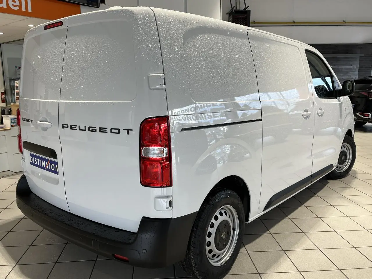 Vue 3/4 arrière droite du Peugeot Expert Fourgon blanc 2024 avec portes arrière battantes et jantes tôles grises.