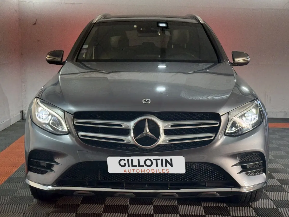 Vue frontale d'un Mercedes GLC 250 Fascination 4Matic gris foncé avec phares LED allumés en intérieur.