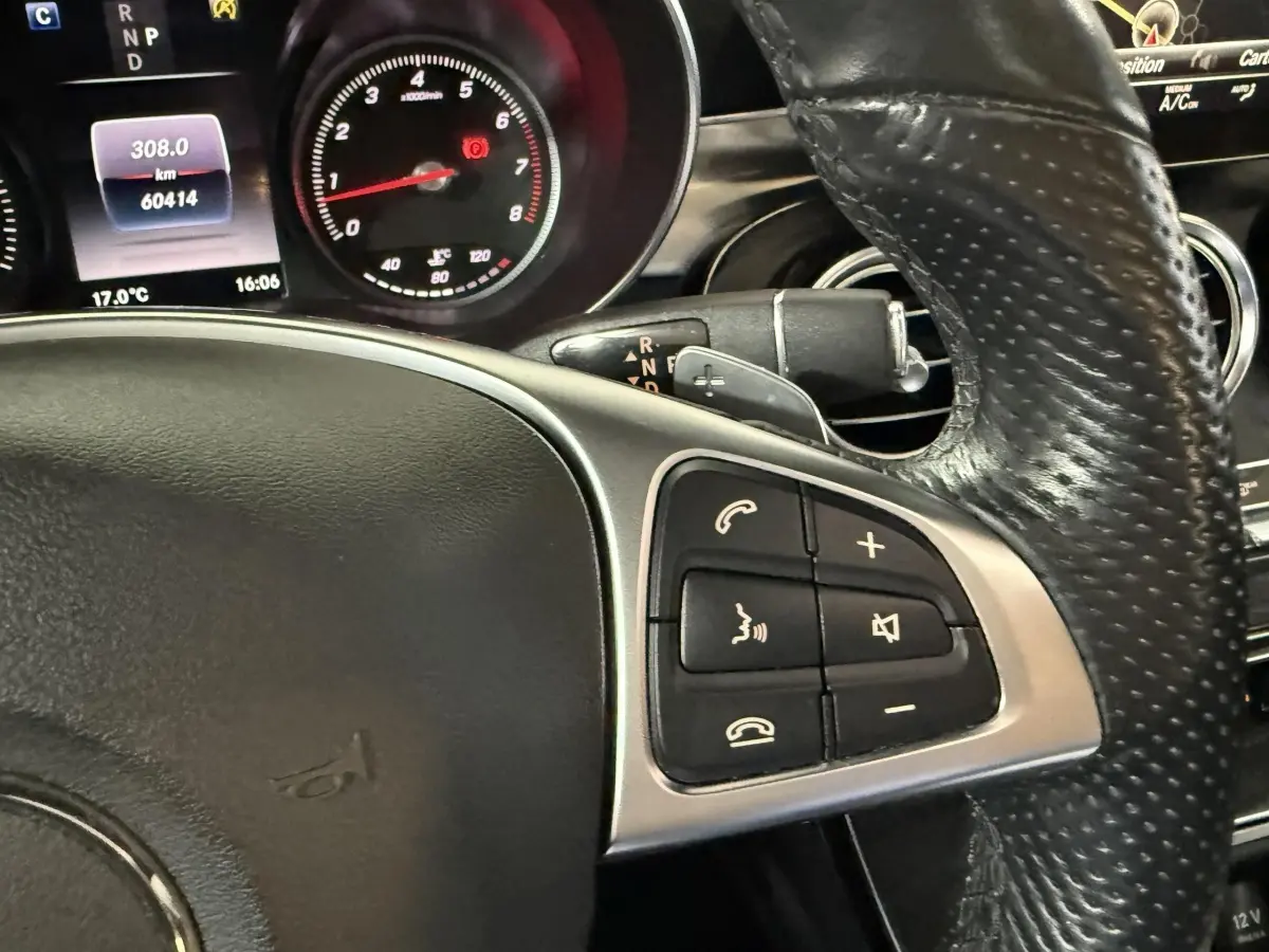 Gros plan sur le volant cuir perforé et les commandes multifonctions du tableau de bord du Mercedes GLC 250 Fascination gris foncé.