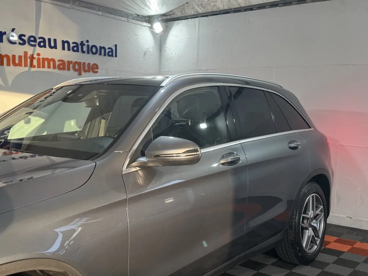Vue côté droit avant d'un Mercedes GLC 250 Fascination 4Matic gris foncé avec rétroviseur chromé et jantes alliage.