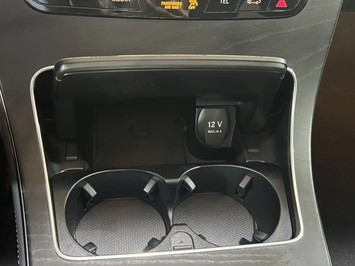 Gros plan sur la console centrale noire du Mercedes GLC 250 Fascination 2019 avec prise 12V et porte-gobelets.