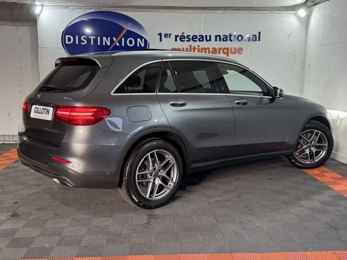 Mercedes GLC 250 Fascination gris foncé en 3/4 arrière droit, avec jantes alliage et feux arrière LED allumés.