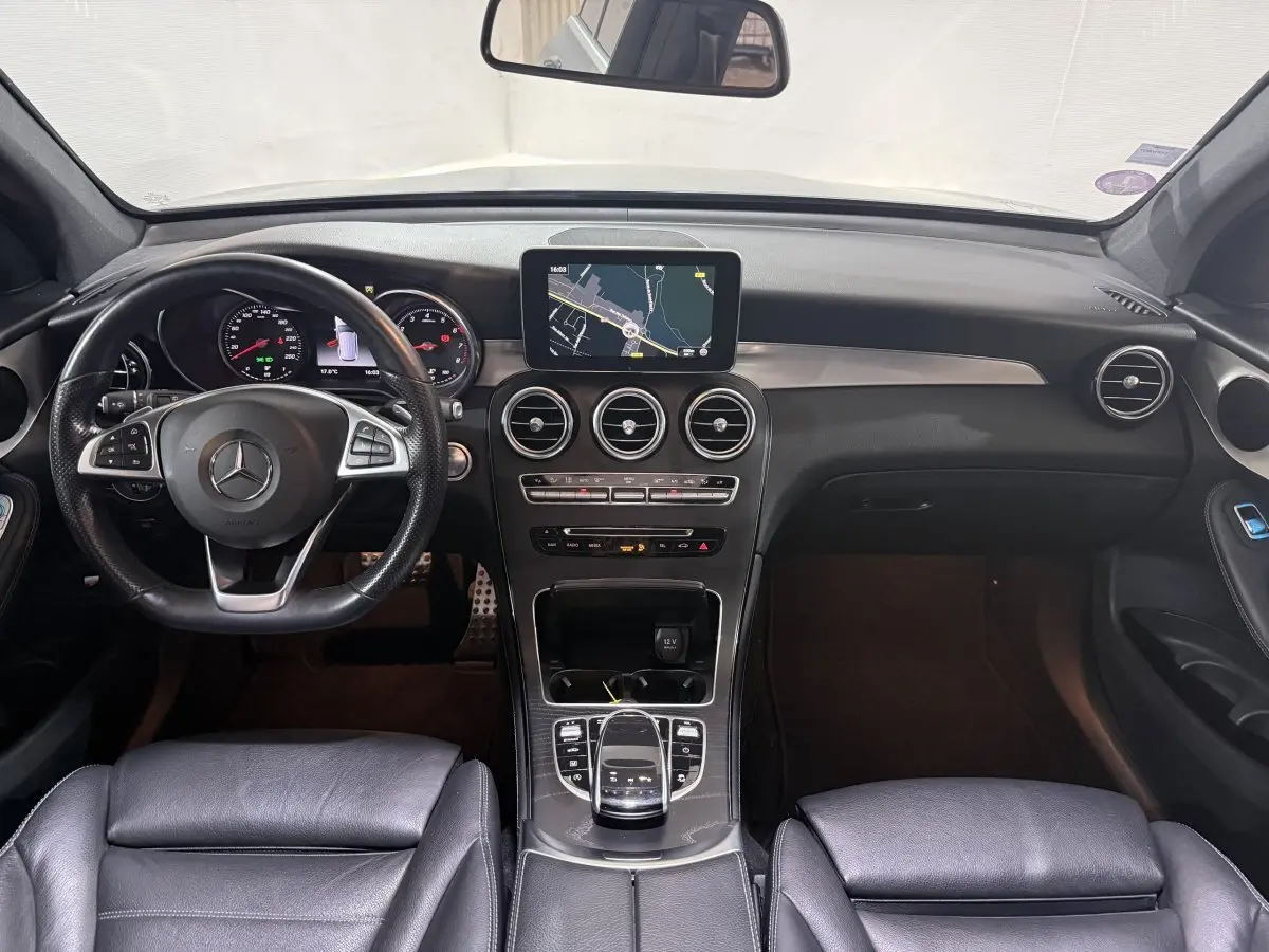 Vue intérieure avant du tableau de bord et volant cuir noir d'une Mercedes GLC 250 Fascination 2019 avec écran central de navigation.