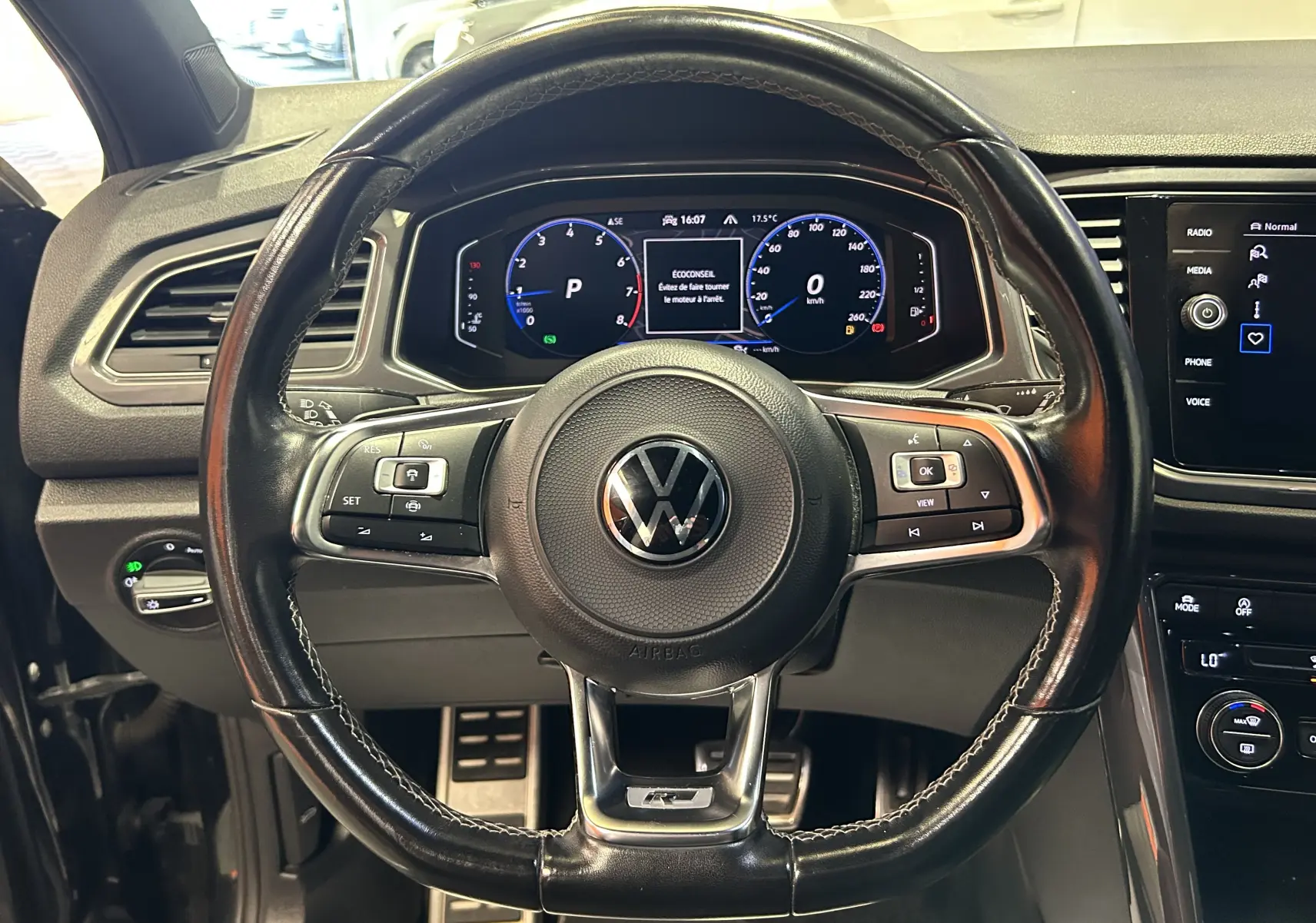 Vue centrée sur le volant noir en cuir du Volkswagen T-Roc 2020 avec tableau de bord numérique et commandes intégrées.