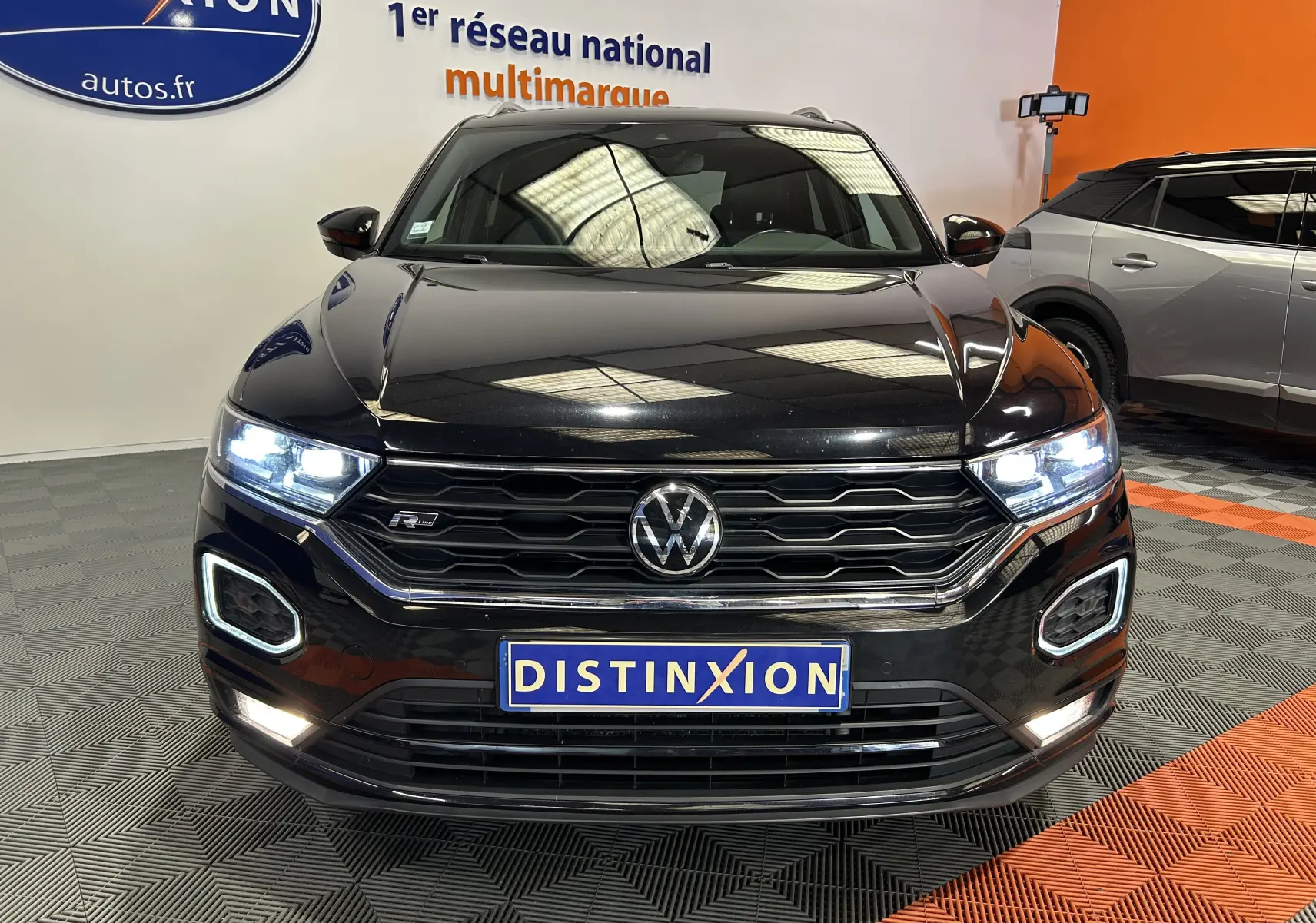 Vue de face d’un Volkswagen T-Roc noir TSI 150ch R-Line avec phares LED allumés et calandre hexagonale distinctive.