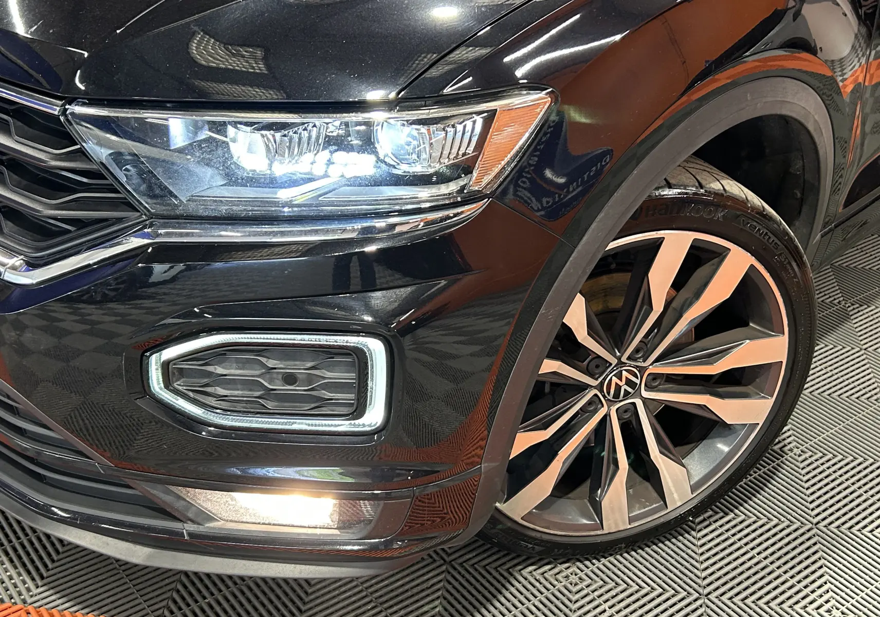 Gros plan sur l'avant droit noir du Volkswagen T-Roc 2020 avec phare LED allumé et jante alliage distinctive.