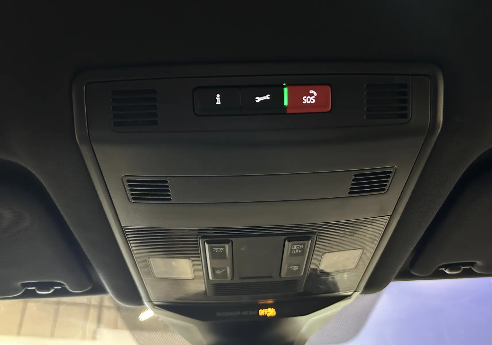 Vue en contre-plongée du panneau de commandes au plafond intérieur du Volkswagen T-Roc noir, avec bouton SOS illuminé en rouge.
