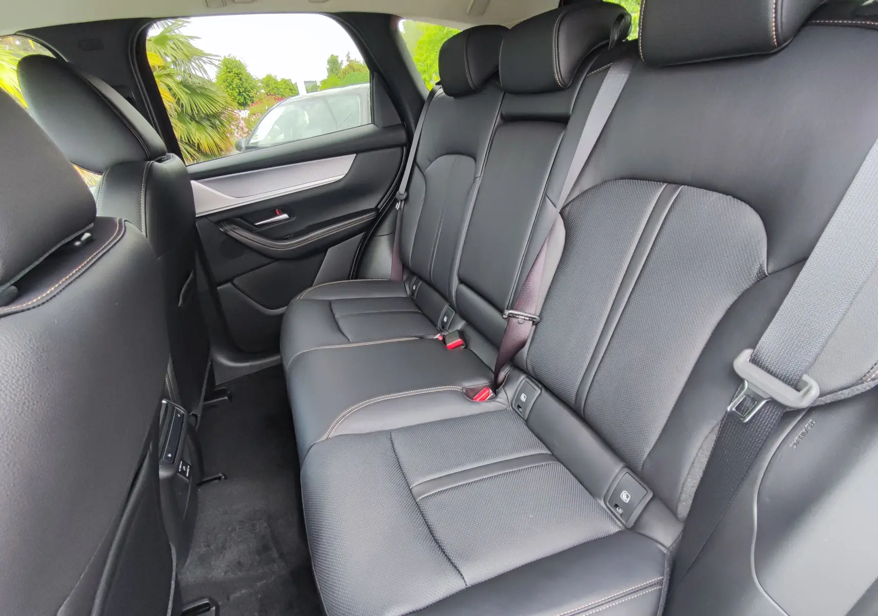 Vue intérieure arrière du Mazda CX-60 2024, sièges en cuir noir avec surpiqûres contrastantes et ceintures grises.