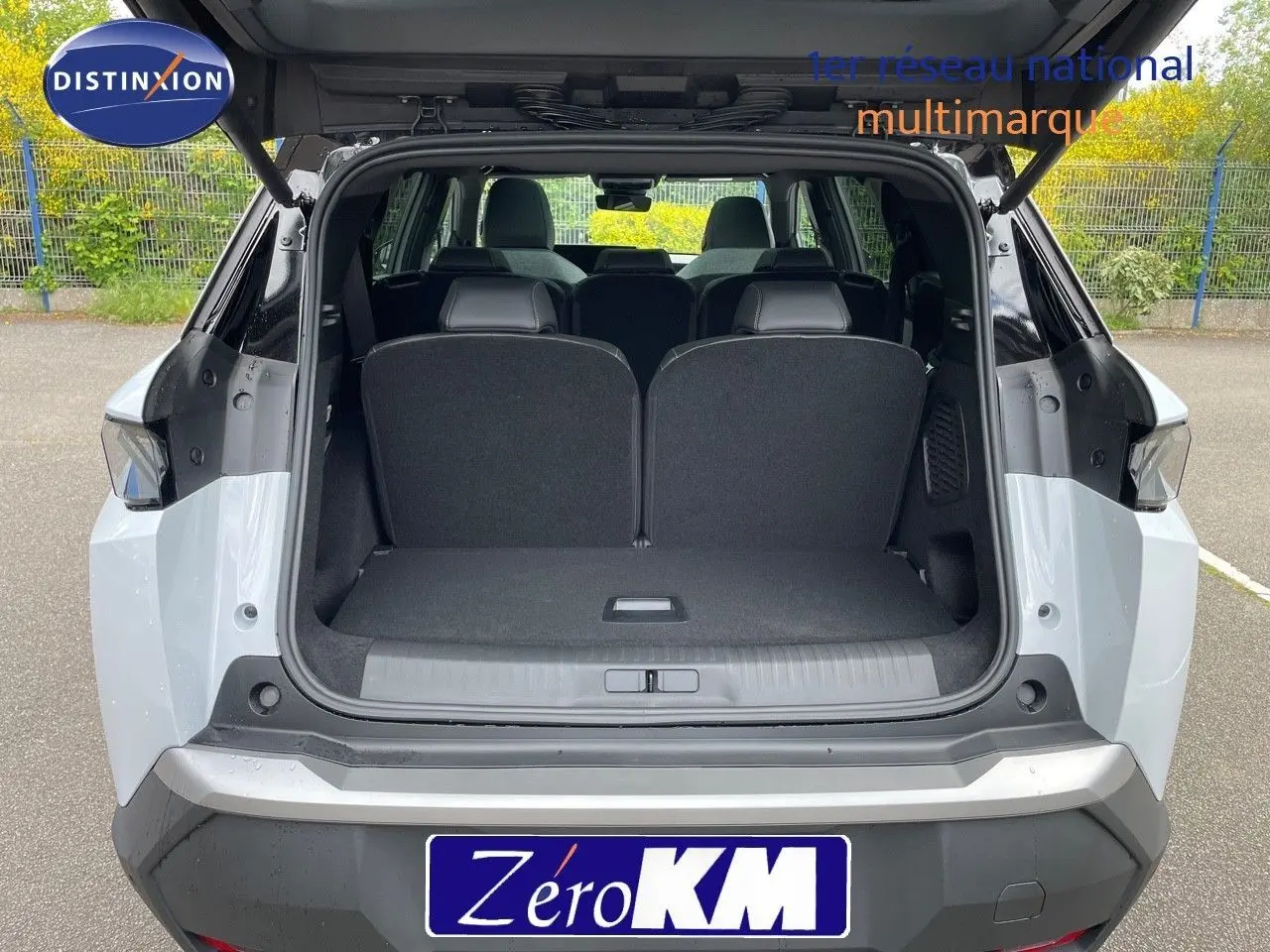 Vue arrière du Peugeot 5008 Hybrid blanc Okenite avec toit noir, coffre ouvert montrant les sièges arrière.