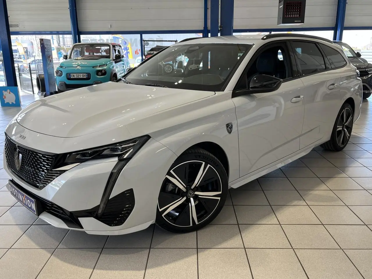 Peugeot 308 SW BlueHDi blanc okenite vue 3/4 avant droit, calandre noire et jantes alliage 18 pouces.